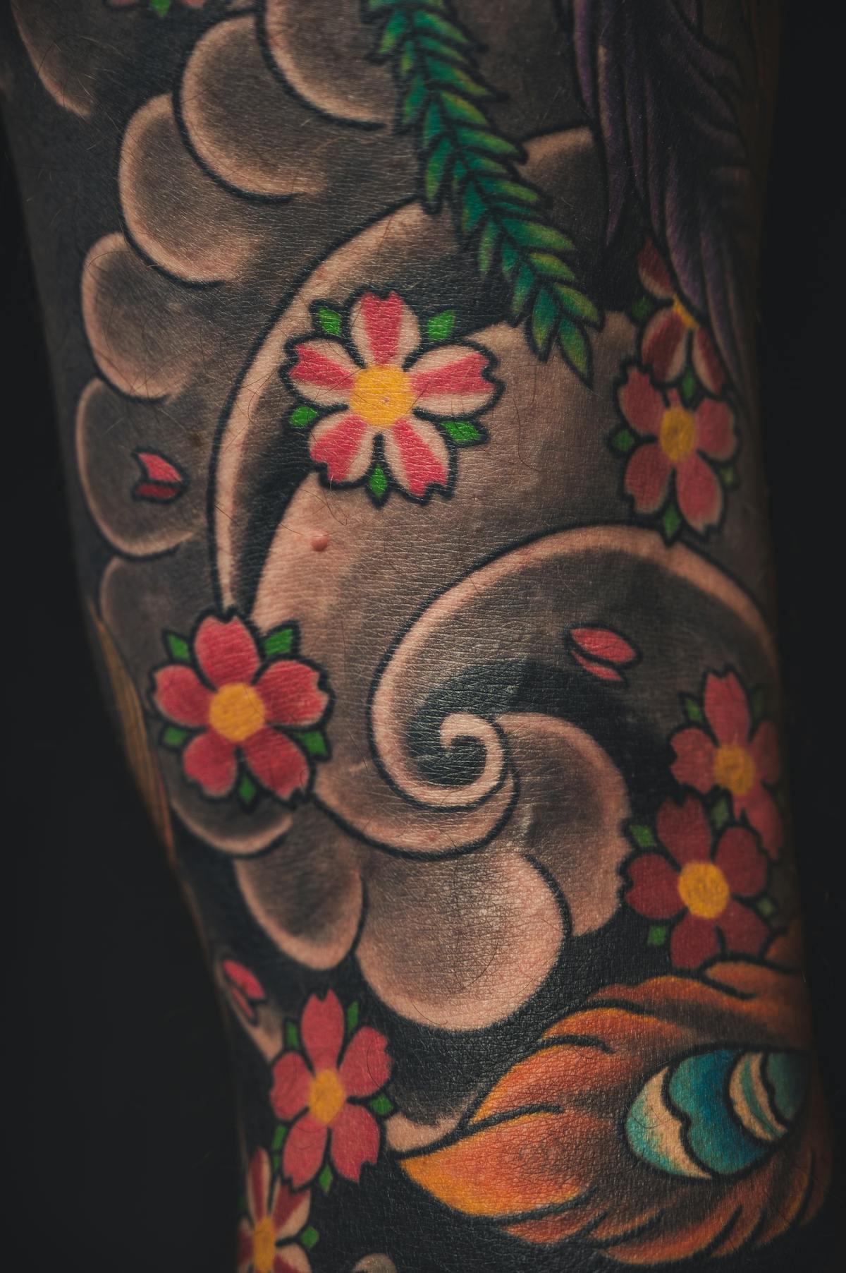 Japanese-style color sleeve with sakura blossoms, dense linework, fresh ink.