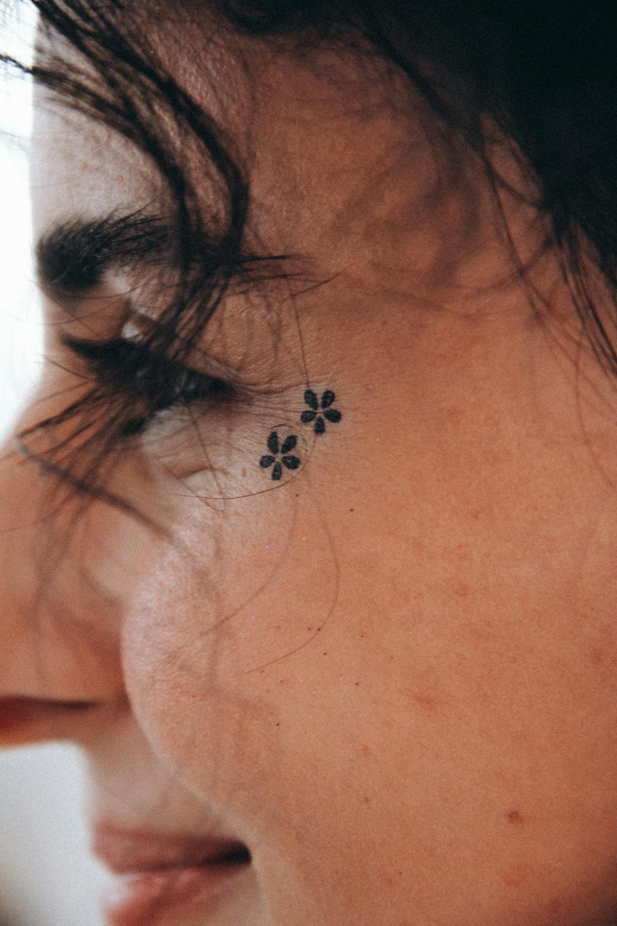 Micro fineline floral cluster placed on the cheek, soft healed lines.